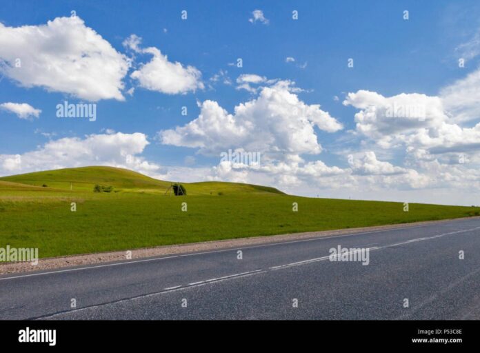 road-in-the-field-long-distance-trail-in-the-field-beautiful-green-hills-blue-sky-with-fluffy-clouds-P53C8E Road in the field, long distance trail in the field. Beautiful green ...